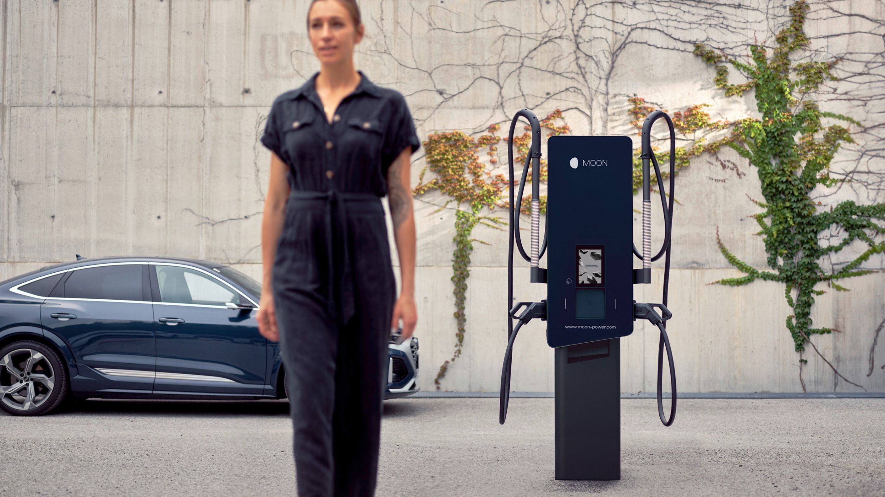 Жена минава пред кола и зарядна станция