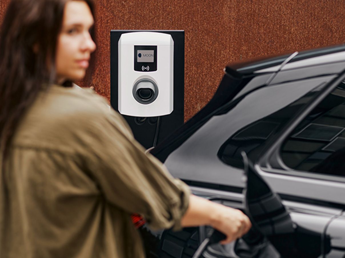 Жена, която поставя заряден накрайник към автомобила