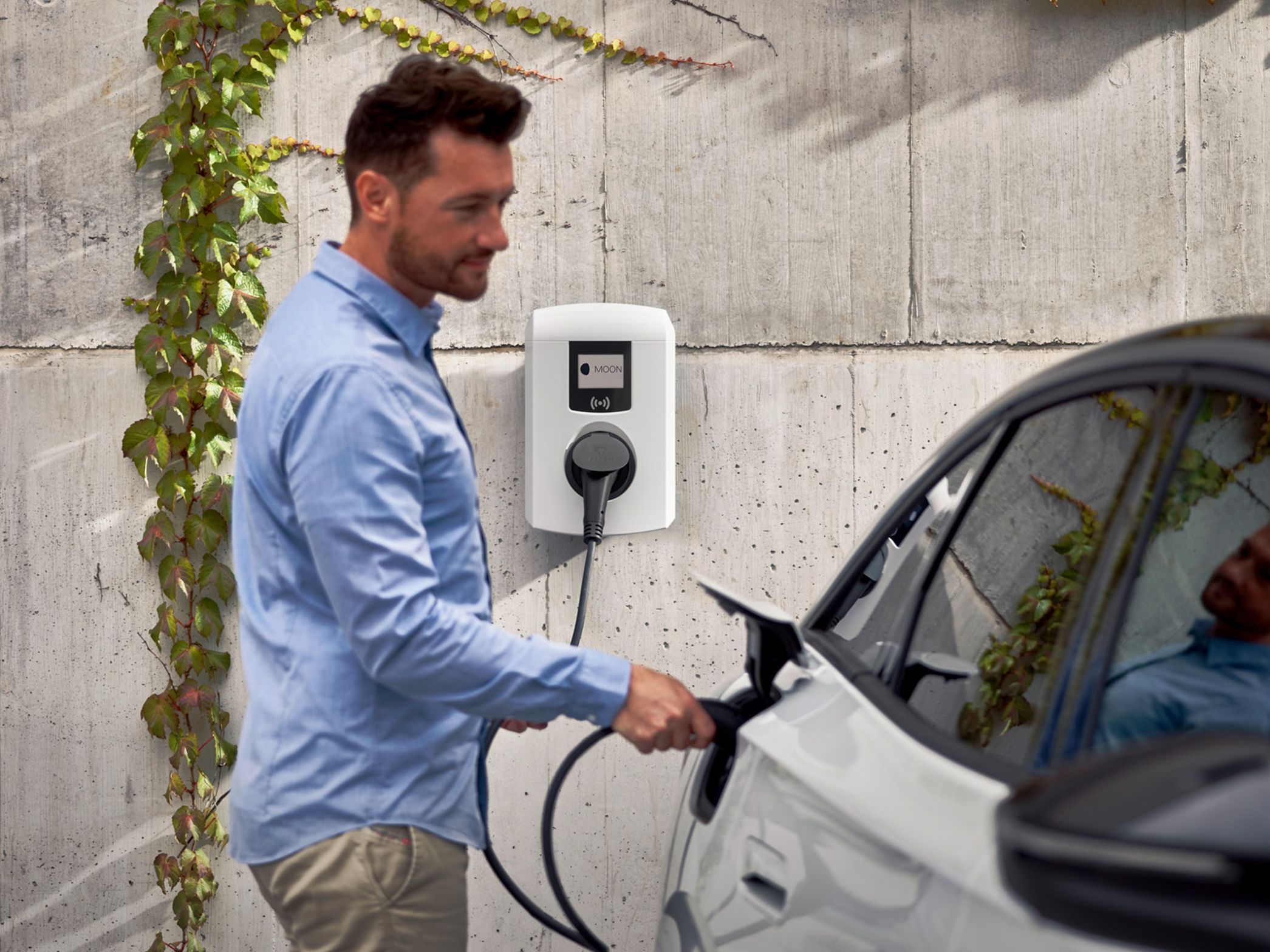 Мъж поставя конектора за зареждане в буксата на автомобила