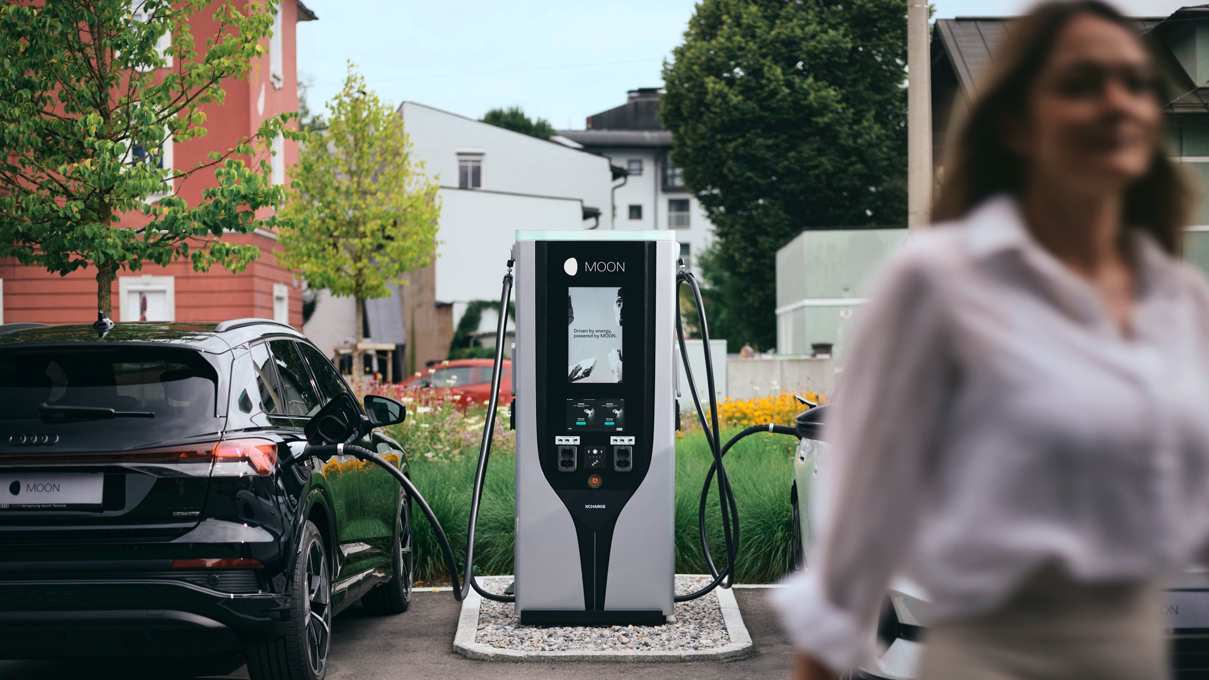 Човек се отдалечава от зарядната станция между две коли