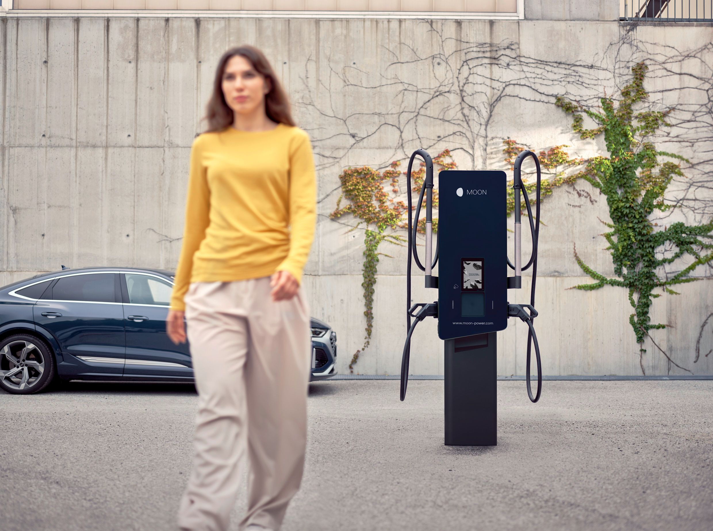 Жена се отдалечава от зарядна станция пред кола