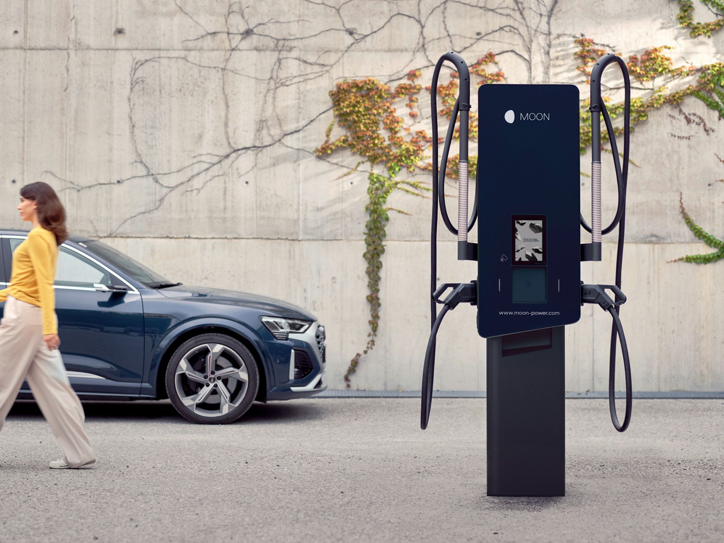 Жена се отдалечава от зарядна станция покрай кола