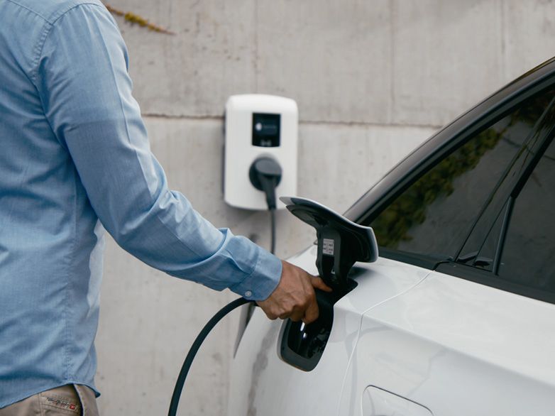 Човек зарежда автомобил от стенна зарядна станция