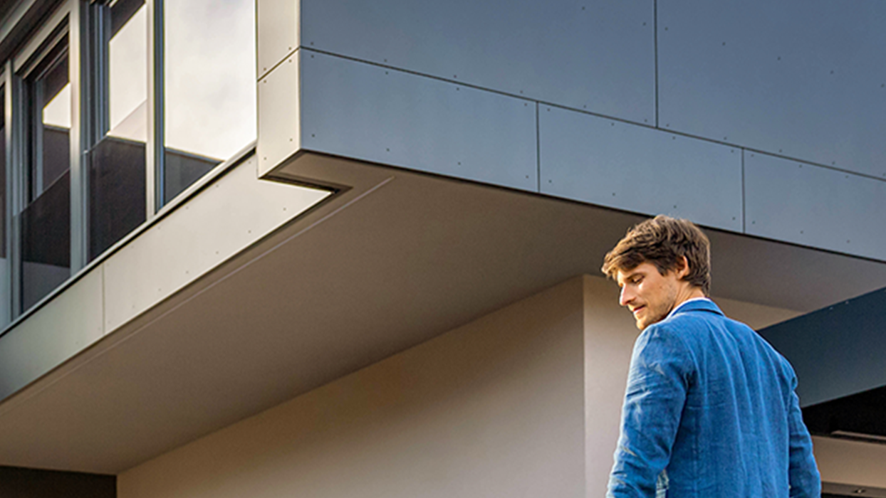 Човек върви към кола с мобилно зарядно в ръка