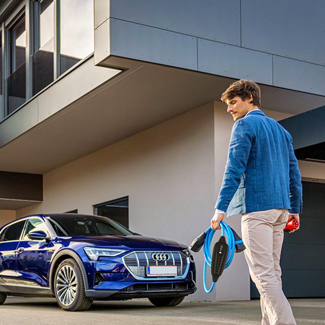 Човек върви към кола с мобилно зарядно в ръка