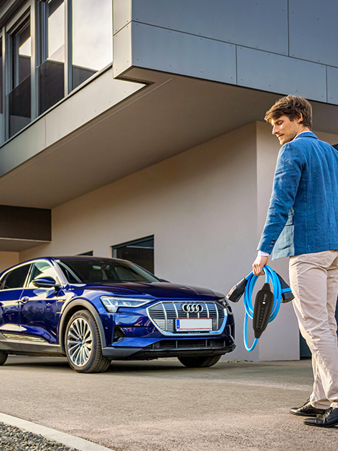 Човек върви към кола с мобилно зарядно в ръка