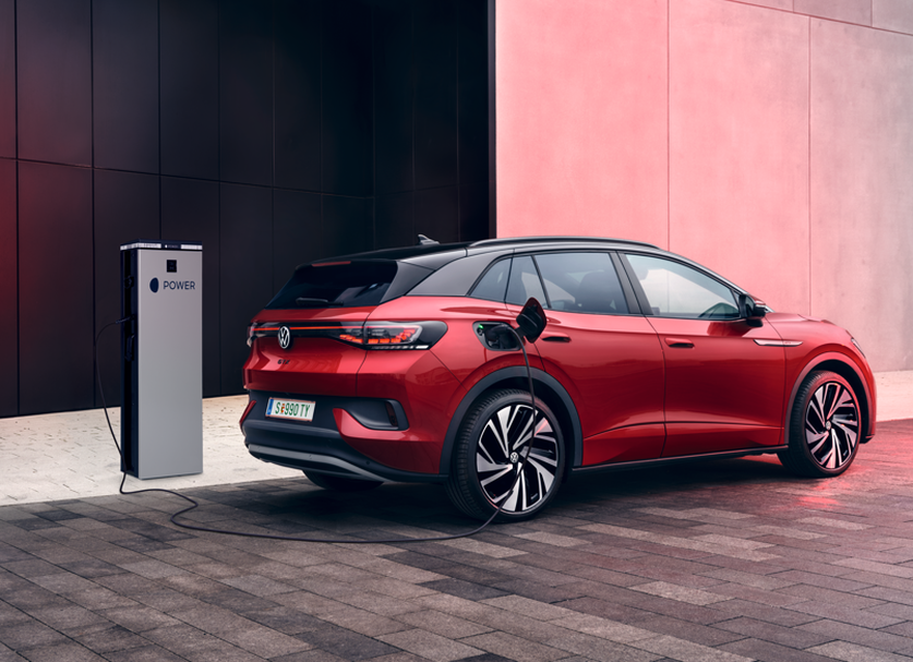 Червен VW ID.автомобил е спрял до зарядна конзола и се зарежда.